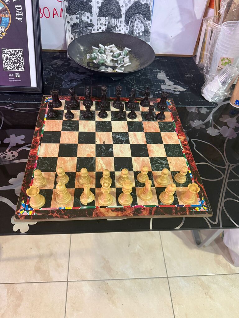A stone chess set laid out on a dark table in the lounge.